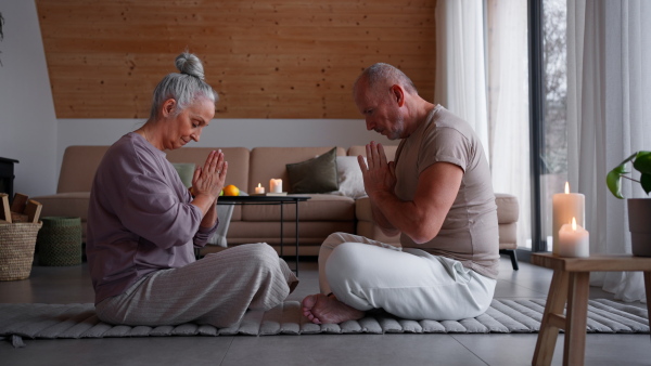 A senior couple meditating together at home.