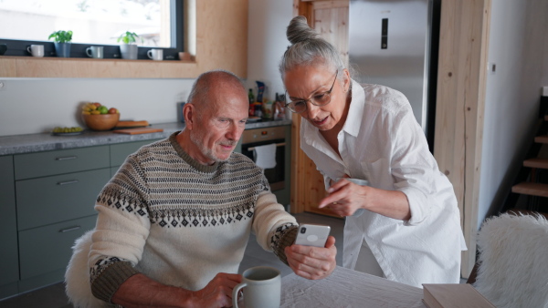 A senior couple spenidng time together in morning in kitchen.