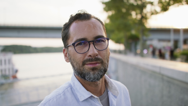 A happy mature man outdoors in riverside, looking at camera.