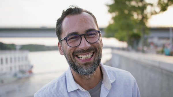 A happy mature man outdoors in riverside, looking at camera.