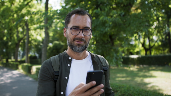 A handsome mature man walking and talking on phone in park.