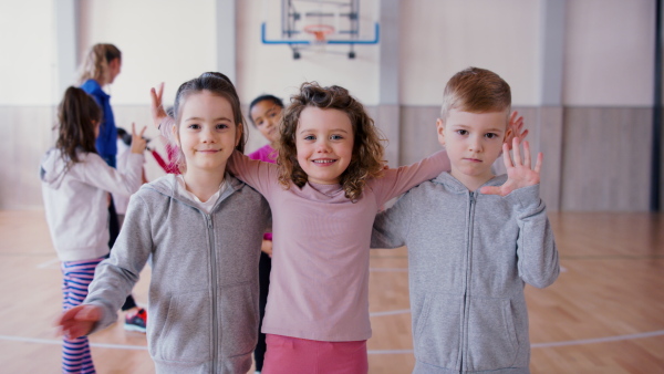 A group of happy pupils looking at cmaera indoors in gym during PE class