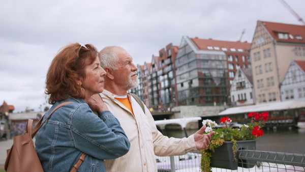 A happy senior couple tourists outdoors in historic town