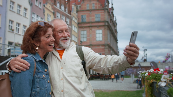 A happy senior couple tourists taking selfie outdoors in historic town