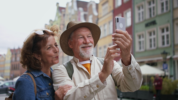 A happy senior couple tourists taking selfie outdoors in historic town