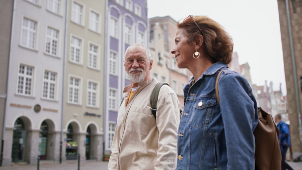 A happy senior couple tourists outdoors in historic town