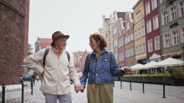 A happy senior couple tourists outdoors in historic town