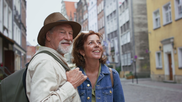 A happy senior couple tourists outdoors in historic town