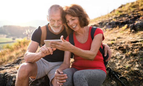 A senior tourist couple hikers in nature, taking selfie.