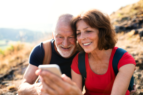 A senior tourist couple hikers in nature, taking selfie.