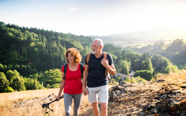 A senior tourist couple travellers hiking in nature, walking and talking.