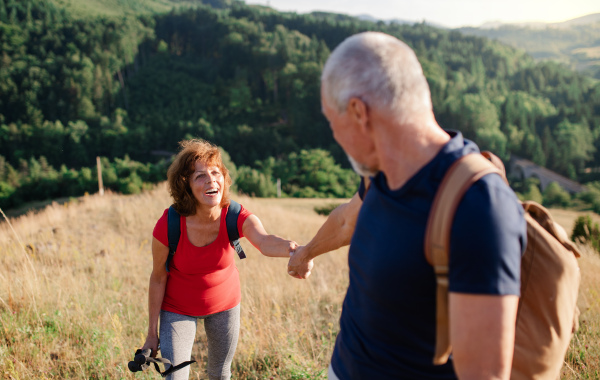 A senior tourist couple travellers hiking in nature, walking and talking.