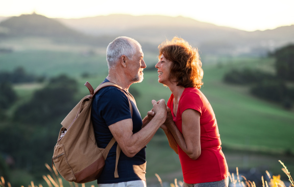 Senior tourist couple hikers with backpack standing in nature, resting. Copy space.