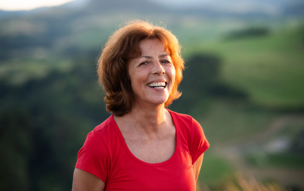 A portrait of senior tourist woman hiker standing in nature. Copy space.