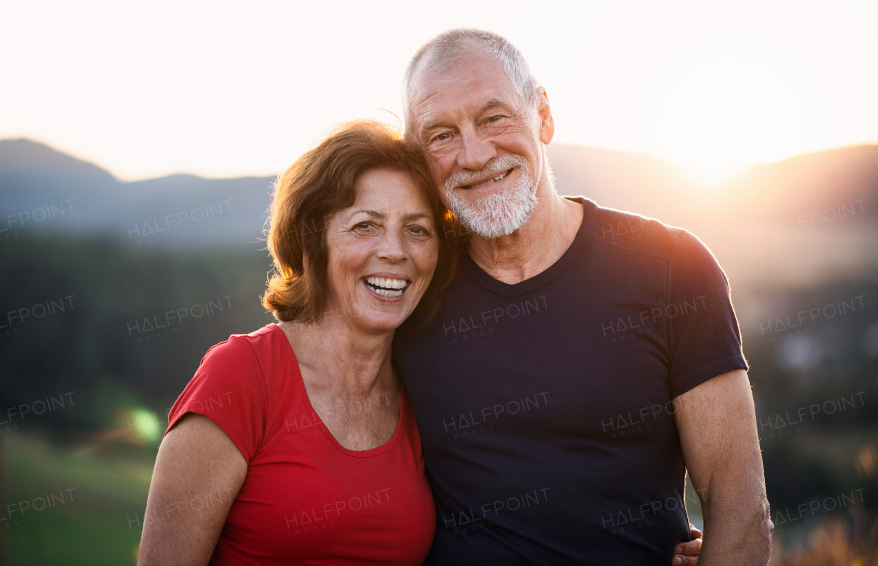 Front view portrait of senior tourist couple hikers standing in nature, looking at camera.