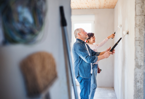 Happy senior couple painting walls in new home, relocation concept.