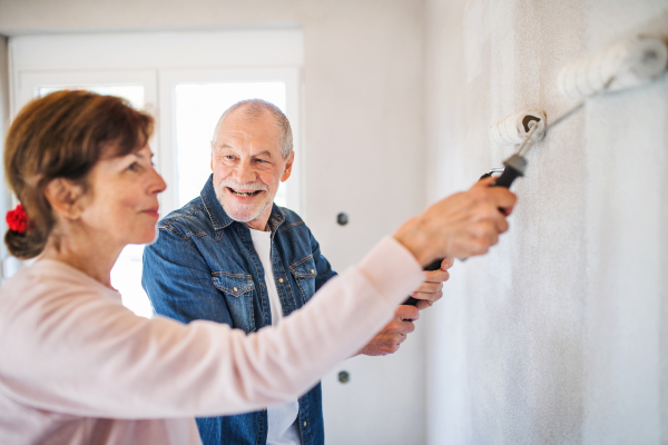 Happy senior couple painting walls in new home, relocation concept.