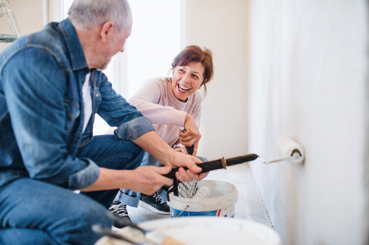 Happy senior couple painting walls in new home, relocation concept.