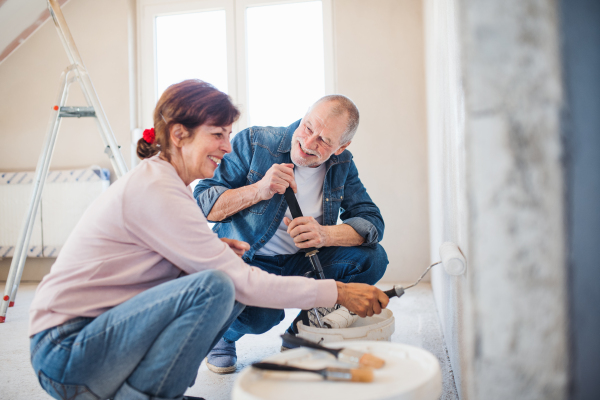 Happy senior couple painting walls in new home, relocation concept.