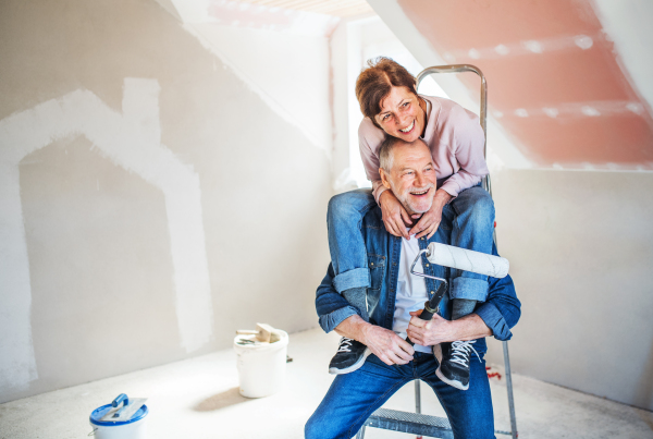 Portrait of cheerful senior couple painting walls in new home, having fun. Relocation concept.