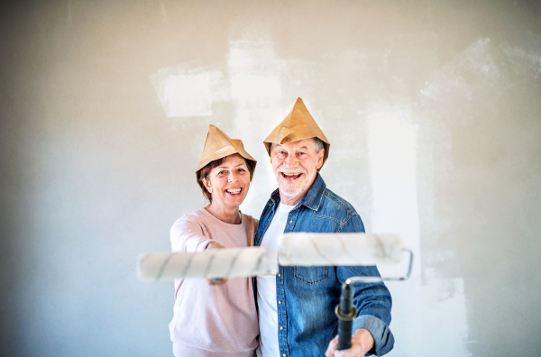 Portrait of cheerful senior couple painting walls in new home, having fun. Relocation concept.