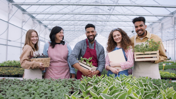 Large group of people working in garden centre posing flower boxes.