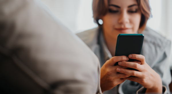 Portrait of a young woman using smartphone, lying on sofa at home, social networks concept.