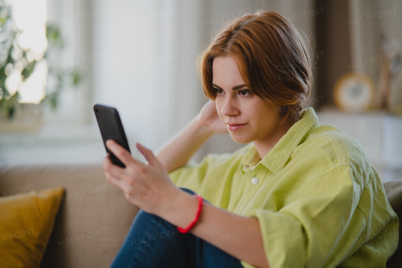 A portrait of young woman using smartphone taking selfie, indoors at home, social networks concept.