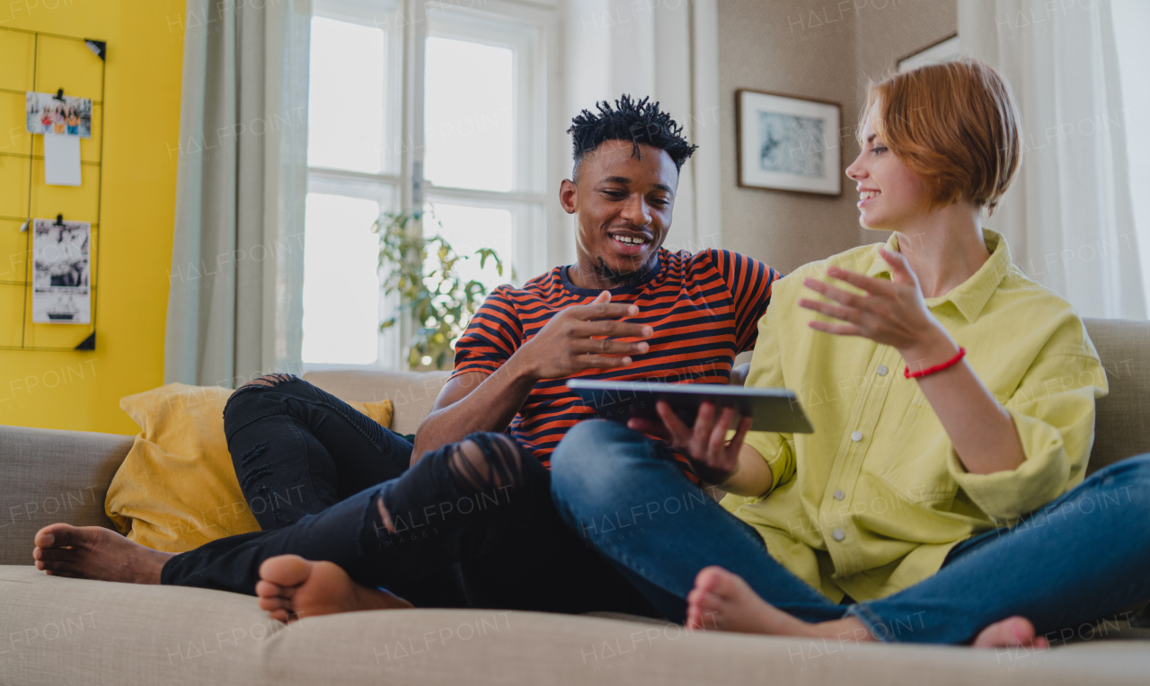 Happy young couple using tablet, having fun at home, checking social media together.