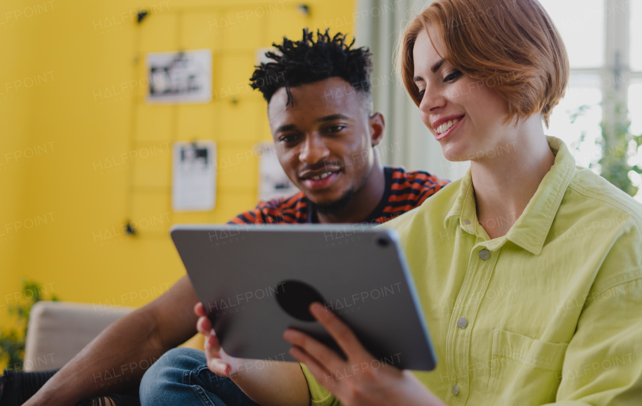 Young biracial couple using a tablet, having fun at indoors at home, checking social networks together.