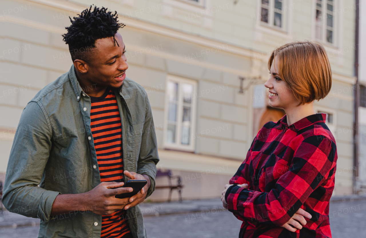 Young man talking to a female friends outdoors in town street.