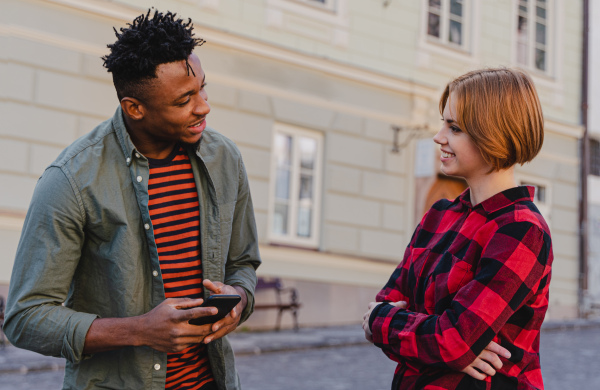 Young man talking to a female friends outdoors in town street.