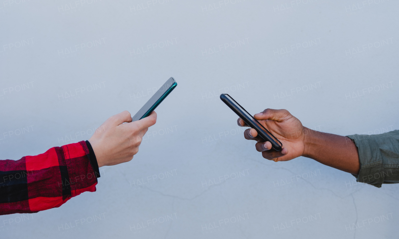 A close up of young mixed couple hands using smartphones on white background