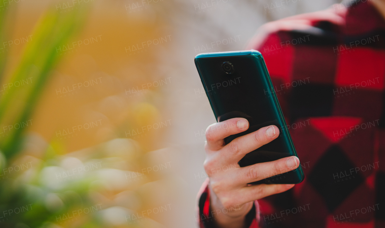 A close up of woman hand using smartphone, outdoors in park. Copy space.