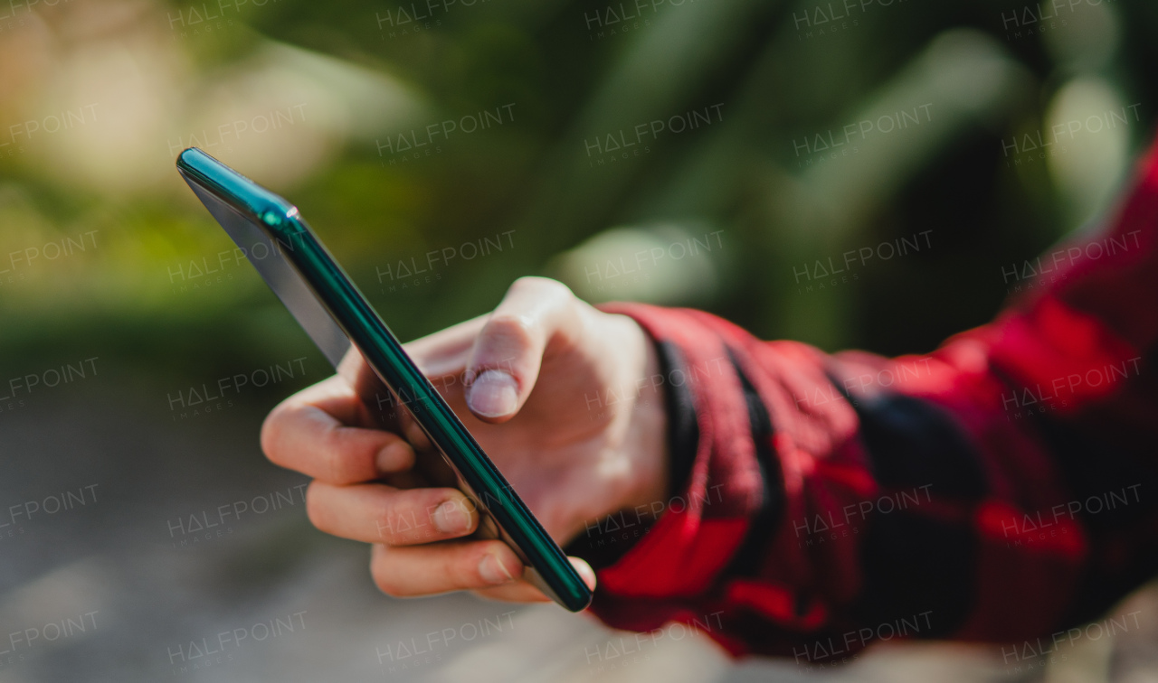 A close up of woman hand using smartphone, outdoors in park. Copy space.