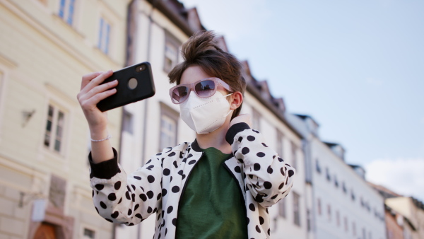 A cheerful teenager taking selfie on street. Social networks and coronavirus concept.