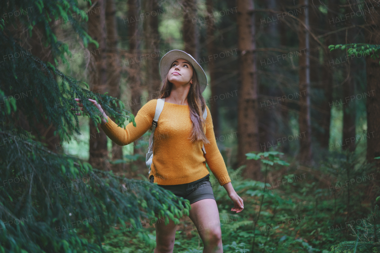 Front view of young woman on a walk outdoors in forest in summer nature, walking.