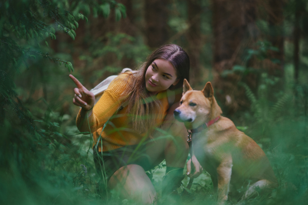 Happy young woman with a dog on a walk outdoors in summer nature.