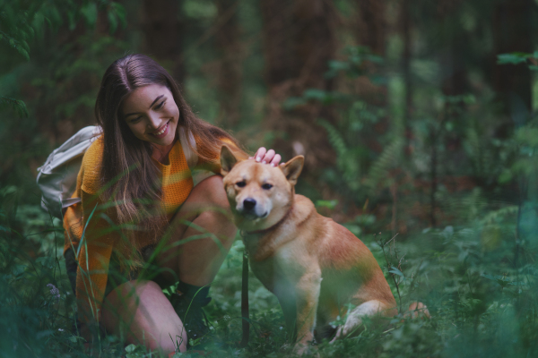 Happy young woman with a dog on a walk outdoors in summer nature.