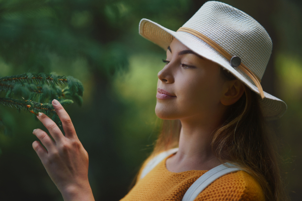 Side view of young woman on a walk outdoors in forest in summer nature, daydreaming.