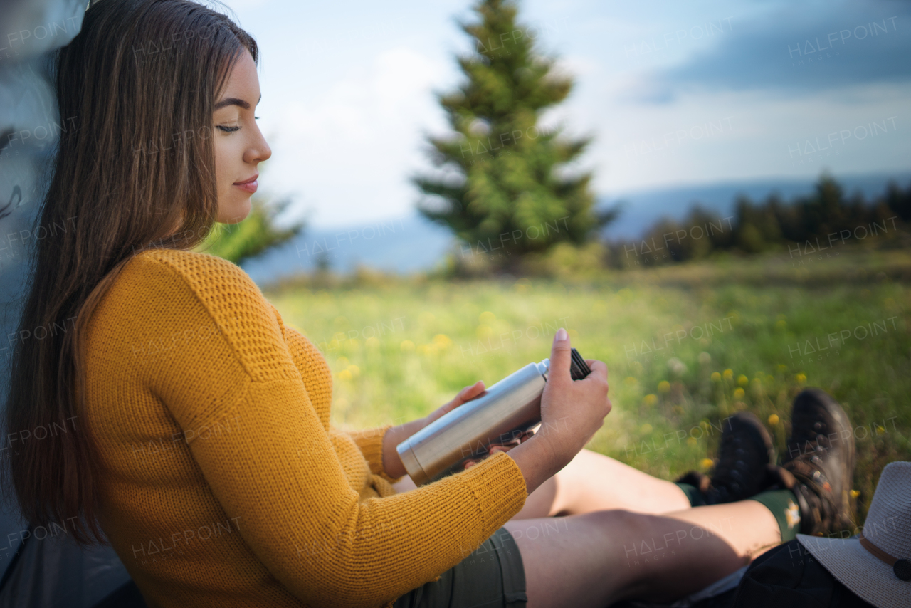 Side view of young woman outdoors on meadow in summer nature, resting.