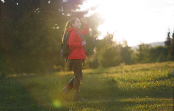 Side view of young woman on a walk outdoors on meadow in summer nature, walking.