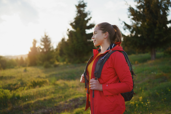 Side view of young woman on a walk outdoors on meadow in summer nature, walking.