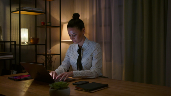 A mid adult business woman working on laptop in office at night.