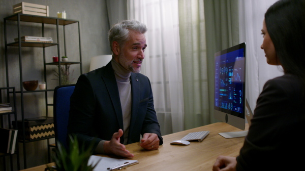 A mature financial advisor consulting with his client indoors in office.