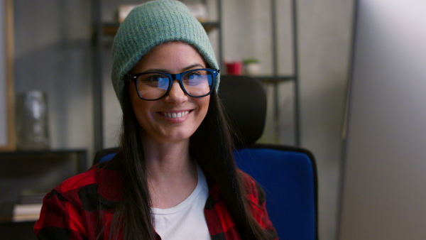 A close up of happy female video editor looking at camera indoors in creative office studio.