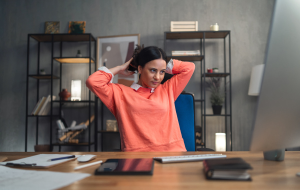 A happy mid adult woman working indoors in office.