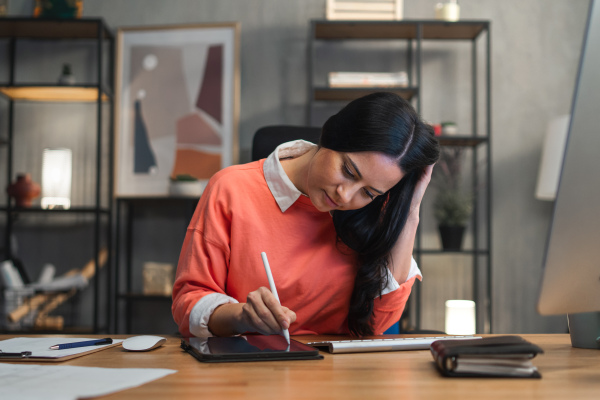 A happy mid adult woman working indoors in office.