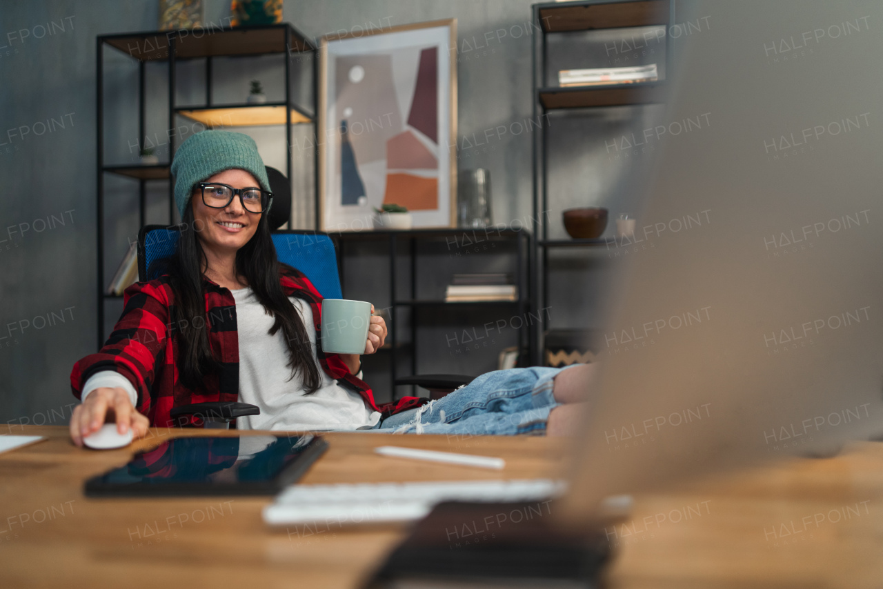 A female video editor working with feet up indoors in creative office studio.