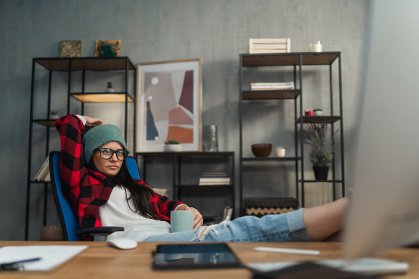 A female video editor resting with feet up indoors in creative office studio.